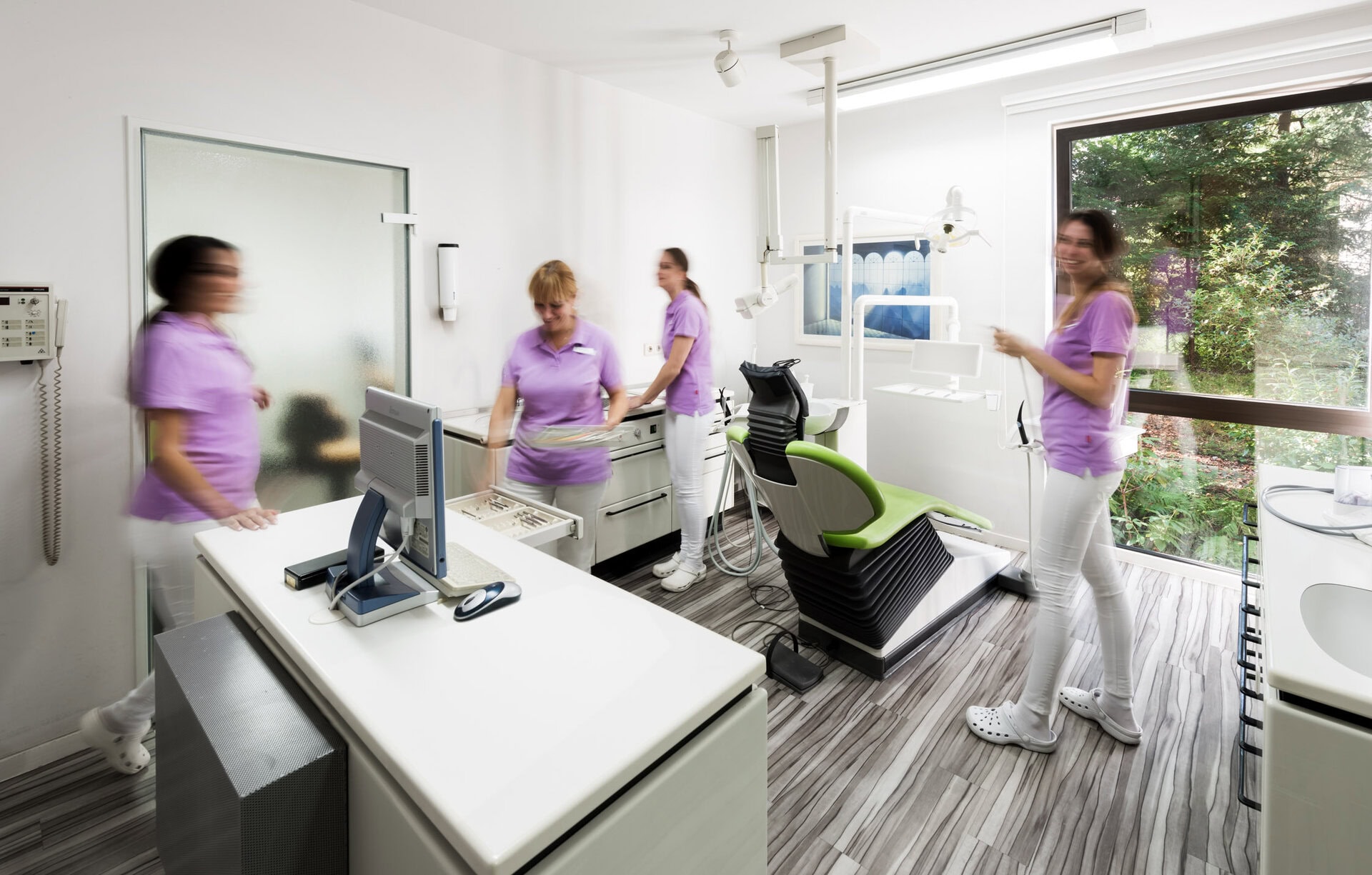 Zahnarztpraxis mit zahnärztlichem Team, Behandlungsraum mit modernen Geräten und großen Fenstern, freundliche.