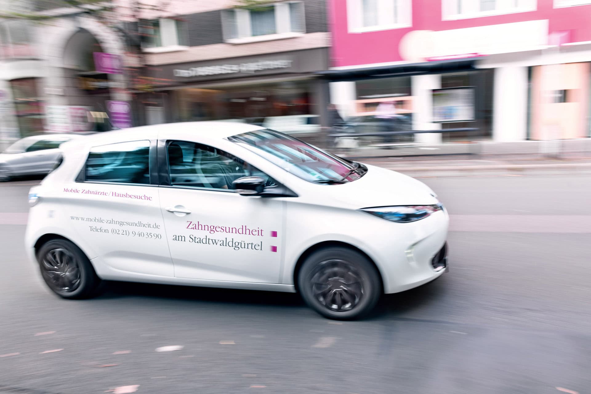 Zahnarztwagen mit Praxislogo auf der Straße, mobile Zahngesundheitsberatung vor Ort.